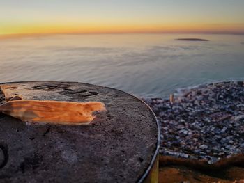 Close-up of sea shore against sky during sunset