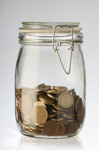 Close-up of coins in jar against white background