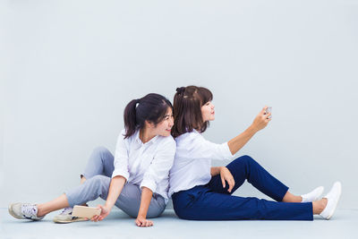 Side view of women sitting against white background