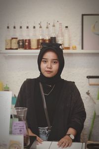 Portrait of young woman using mobile phone while standing in cafe