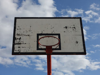 Basketball hoop on an outdoor court with sky and clouds background