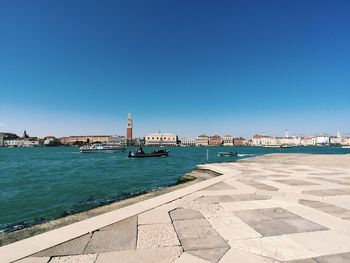 View of buildings by sea against blue sky