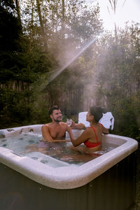 Couple sitting in hot tub in forest