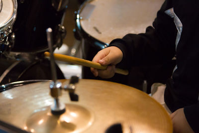 Midsection of man playing drum set