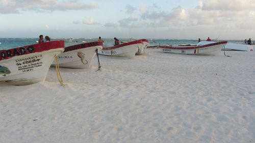 Boats moored on beach against sky