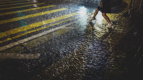 Low section of man with umbrella on wet road