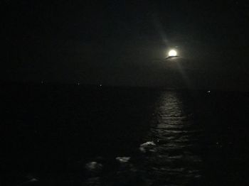 Illuminated sea against sky at night