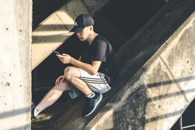 Young man sitting on wall