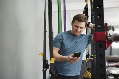 Mid adult man in gym using cell phone