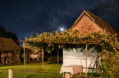 House by trees against sky at night