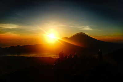 Silhouette people on mountain against sky during sunset