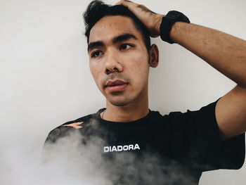 Portrait of young man standing against white background