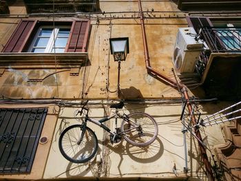 Low angle view of bicycle hanging on building