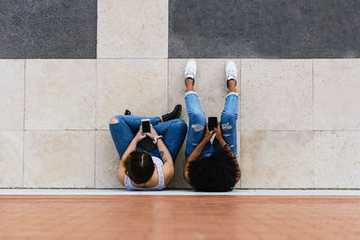 Directly above shot of female friends sitting on footpath