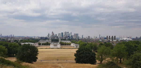 View of trees and buildings against cloudy sky