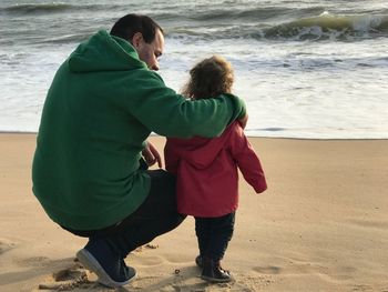 Rear view of father with daughter on sea shore