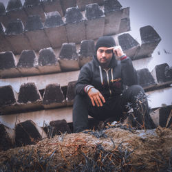 Full length portrait of young man sitting in winter