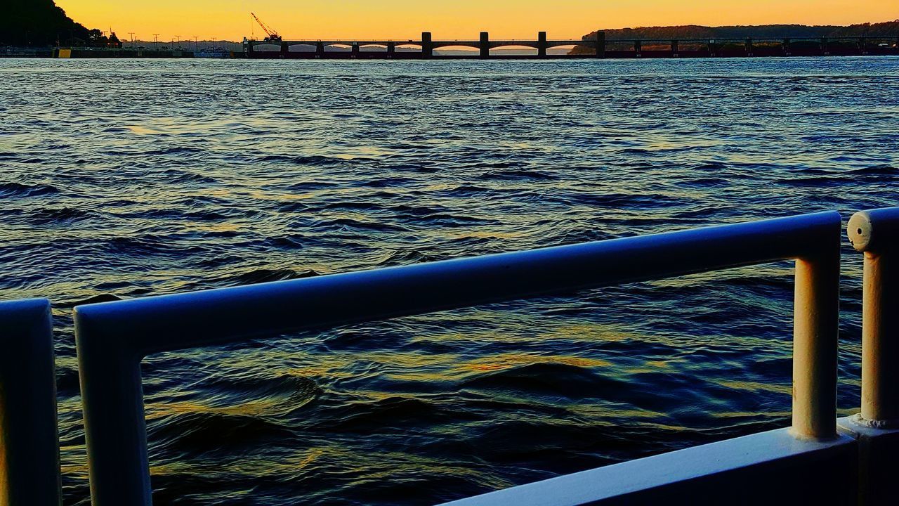 CLOSE-UP OF METAL RAILING BY SEA