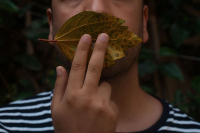 Close-up of man covering lips with leaf
