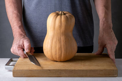 Midsection of man cutting pumpkin on table