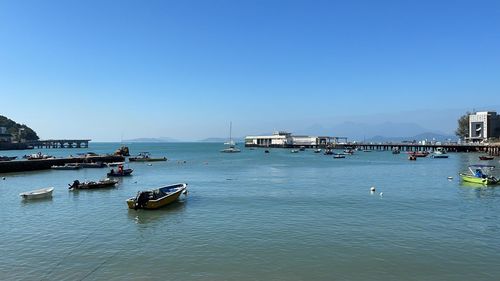 Boats in sea against clear blue sky