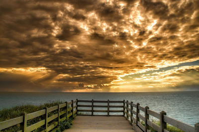 Pier on sea against cloudy sky