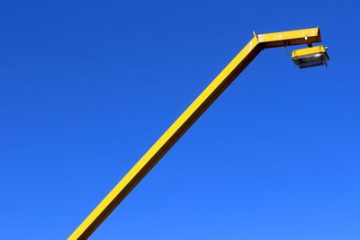 Low angle view of city light against clear blue sky