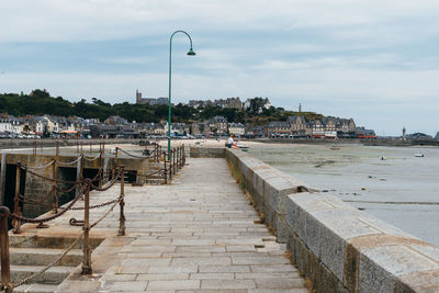 Teenage girl sitting on retaining wall by sea