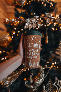 Female hands holding a cup of coffee or tea with a christmas cozy design. winter holiday decor