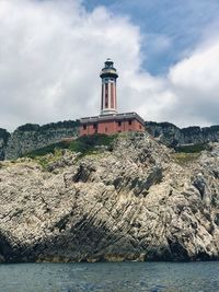 Lighthouse by sea against sky