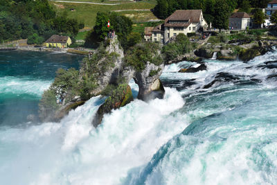 Scenic view of waterfall by sea against buildings