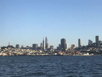 Sea by buildings against clear sky