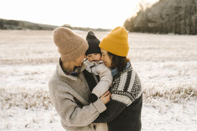 Side view of friends standing on snow covered land