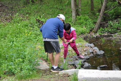 Rear view of boy and girl fishing by pond