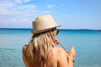 Rear view of woman wearing hat against sea