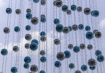 Low angle view of electric lights hanging on against sky