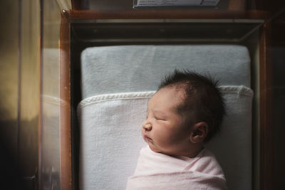 High angle view of newborn baby girl sleeping in crib at hospital
