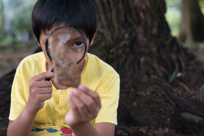 Close-up boy looking at leaf through magnifying glass