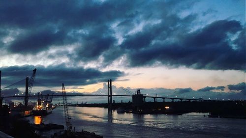 Silhouette of bridge over river against cloudy sky