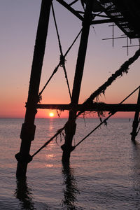 Silhouette tree by sea against sky during sunset