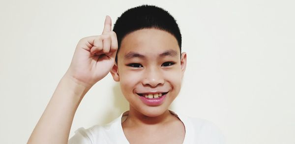 Portrait of smiling boy gesturing against white background