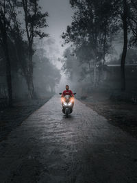 Rear view of man riding motorcycle on road