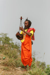 Man holding umbrella on field against clear sky