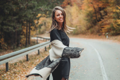 Portrait of woman standing on road during autumn