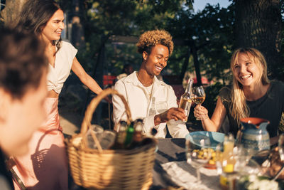 Happy male and female friends toasting drinks during dinner party in back yard