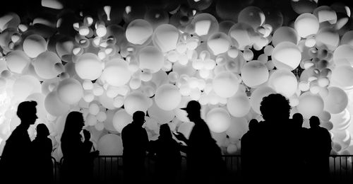 Silhouette people against balloons at night