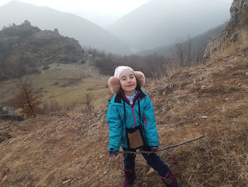 Cute young girl, kid posing with winter ear cap in the outdoors