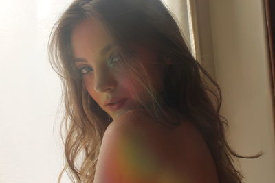 Close-up portrait of young woman with spectrum on body at home