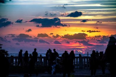 Silhouette people standing against sea during sunset