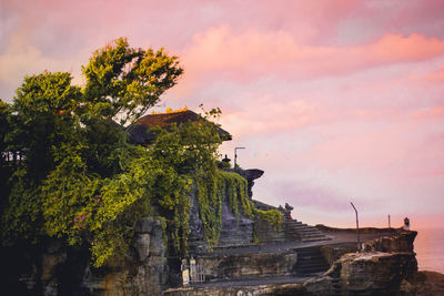 Built structure and trees against sky during sunset